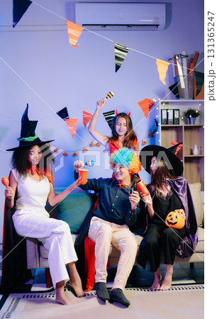 Joyful office Halloween party with coworkers in costumes, celebrating 131365247