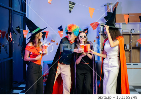 Joyful office Halloween party with coworkers in costumes, celebrating 131365249