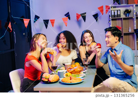 Friends celebrate indoors with food and wine, sharing laughs and toasts at a festive gathering. Friends celebrate indoors with food and wine, sharing laughs and toasts at a festive gathering. 131365256