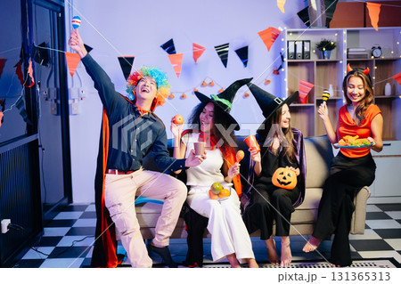Joyful friends in vibrant Halloween costumes share drinks and laughter at a festive indoor party. Joyful friends in vibrant Halloween costumes share drinks and laughter at a festive indoor party. 131365313