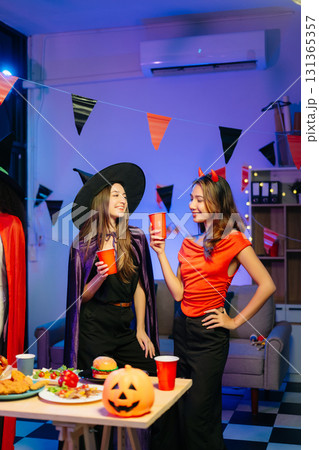 Joyful office Halloween party with coworkers in costumes, celebrating with drinks and laughter, fostering teamwork 131365357