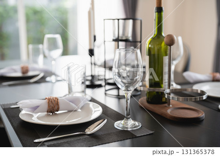 Elegant Dining Table Setting with Wine Bottle and Glassware in Modern Interior, Ideal for Celebrations and Special Occasions Elegant Dining Table Setting with Wine Bottle and Glassware in Modern Interior, Ideal for Celebrations and Special Occasions 131365378