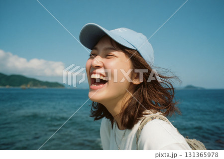 海辺で楽しそうに笑う帽子を被った若い女性 海辺で楽しそうに笑う帽子を被った若い女性 131365978