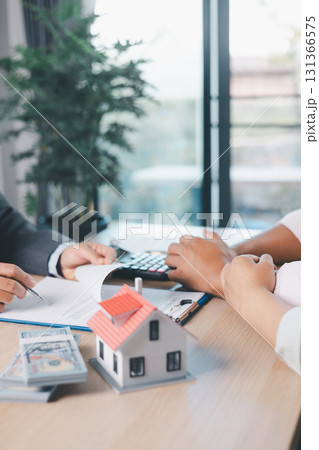 House model on desk with blurred people discussing contract in background, concept of real estate investment, mortgage loan, home ownership, property business and financial agreement. House model on desk with blurred people discussing contract in background, concept of real estate investment, mortgage loan, home ownership, property business and financial agreement. 131366575