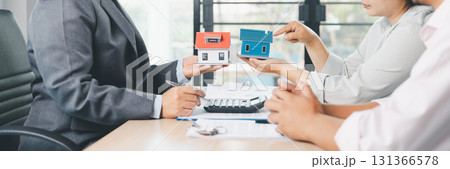 Mortgage consultation panorama with miniature house model in hand, financial advisor meeting clients, property investment, home loan agreement, real estate planning and housing business negotiation. Mortgage consultation panorama with miniature house model in hand, financial advisor meeting clients, property investment, home loan agreement, real estate planning and housing business negotiation. 131366578