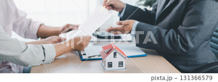 Mortgage consultation panorama with miniature house model in hand, financial advisor meeting clients, property investment, home loan agreement, real estate planning and housing business negotiation. Mortgage consultation panorama with miniature house model in hand, financial advisor meeting clients, property investment, home loan agreement, real estate planning and housing business negotiation. 131366579