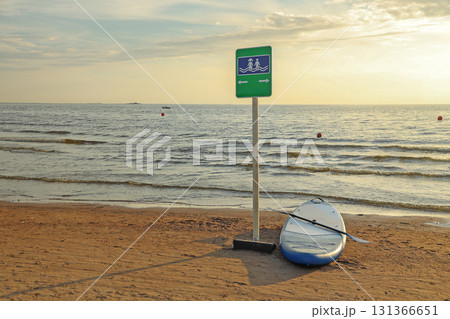 Sign indicating children's swimming area on sea beach and nearby SUP board on sunset Sign indicating children's swimming area on sea beach and nearby SUP board on sunset 131366651