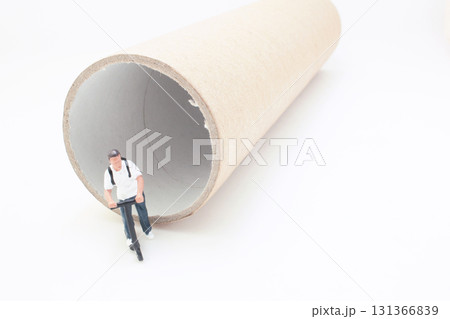 Miniature Man Pushing Scooter Next To Large Cardboard Tube Miniature Man Pushing Scooter Next To Large Cardboard Tube 131366839