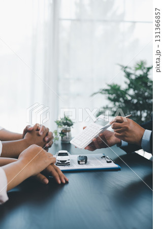 Businessman explaining car loan agreement with calculator, customer discussing auto finance deal at office desk with toy car and document, concept of vehicle loan, insurance or car leasing. car loan. Businessman explaining car loan agreement with calculator, customer discussing auto finance deal at office desk with toy car and document, concept of vehicle loan, insurance or car leasing. car loan. 131366857