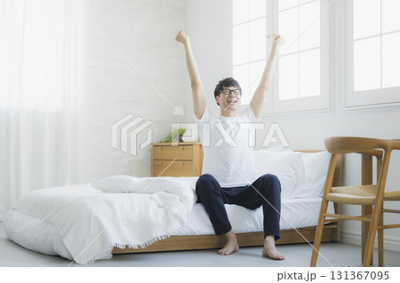 ベッドルームで伸びをする男性 131367095