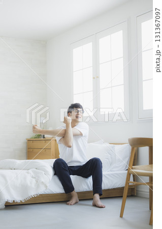 ベッドルームで伸びをする男性 131367097