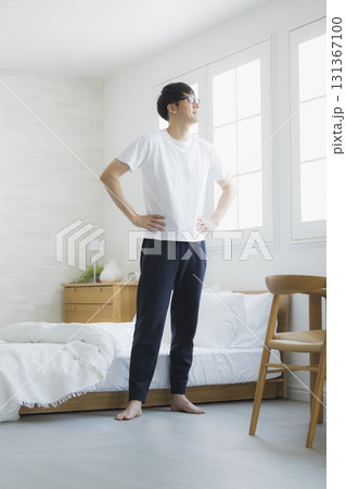 ベッドルームで伸びをする男性 131367100