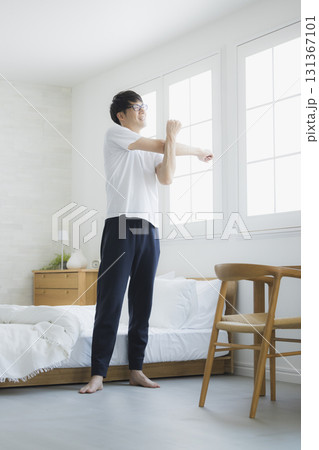 ベッドルームで伸びをする男性 131367101
