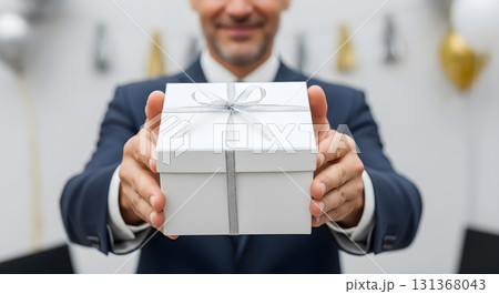 Man in suit offering a white gift box with silver ribbon Man in suit offering a white gift box with silver ribbon 131368043