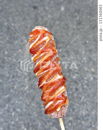 Korean corn dog, a crispy snack coated in a sweet batter, often stuffed with sausage, cheese, or both. Topped with sugar, ketchup, or mustard for a delightful mix of flavors and textures. 131368065