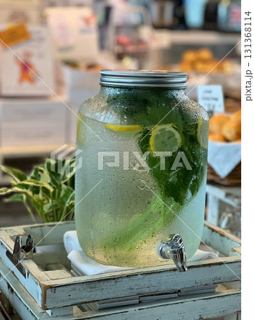A refreshing glass of lemonade with ice cubes, garnished with fresh lemon slices and a sprig of mint, capturing the vibrant yellow color and crisp, citrusy essence. 131368114