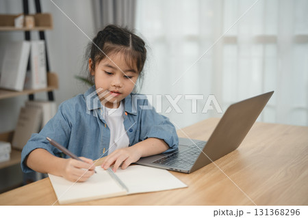 Young Girl Engaged in Creative Writing Activity at Home with Laptop and Notebook in Cozy Workspace Filled with Natural Light and Soft Decor Young Girl Engaged in Creative Writing Activity at Home with Laptop and Notebook in Cozy Workspace Filled with Natural Light and Soft Decor 131368296