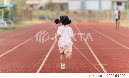 Excited Child With Pigtails Running On Track During Outdoor Sports Practice In Bright Sunshine On Summer Day At School Playground 131369091