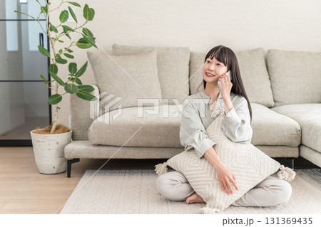 スマホで電話する日本人女性（家,リビング,笑顔） 131369435