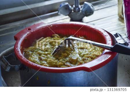 Plastic pot of plum jam. Stirring plum jam 131369705