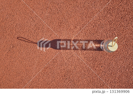 Clear water bottle with wooden cap casting long shadow on red textured surface 131369906