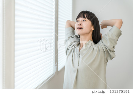 リビングの窓辺に立つ若いアジア人女性（伸び,ストレッチ） 131370191
