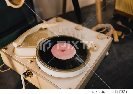 Close up view of vintage record player spinning vinyl record featuring pink label, highlighting nostalgic charm and intricate design of retro music technology. Vintage turntable spinning vinyl record 131370252