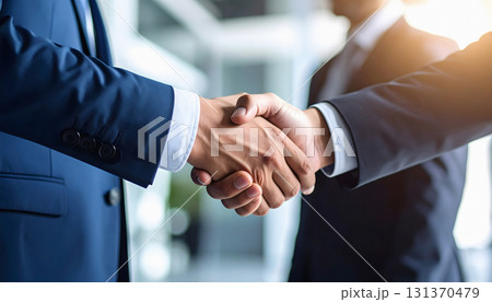 Businessmen handshake under bright light symbolizing trust and success 131370479