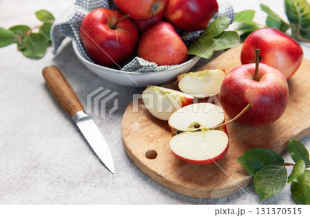 Red apples, whole and sliced, on cutting board 131370515