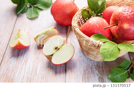 Fresh red apples in basket with green leaves Fresh red apples in basket with green leaves 131370517