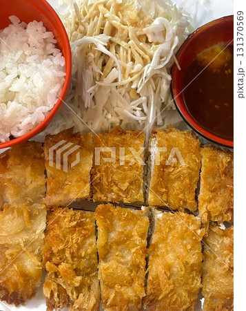 Crispy tonkatsu, a Japanese-style breaded and deep-fried pork cutlet, served with shredded cabbage and drizzled with savory sauce. A delightful balance of crunchy texture and juicy meat. 131370569
