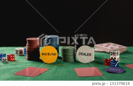 Colorful poker chips, dice, and playing cards set up on a green felt table creating a vibrant gaming atmosphere for casino-themed activities and events 131370618