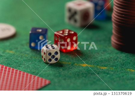 Colorful Dice on a Green Felt Table Surrounded by Poker Chips and Cards at a Casino Game Night Gathering 131370619