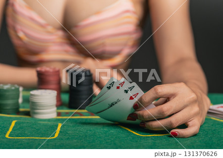 Close-up of Sexy Woman Holding Playing Cards at Table with Poker Chips in Soft Focus Background during Exciting Game Night with Friends Close-up of Sexy Woman Holding Playing Cards at Table with Poker Chips in Soft Focus Background during Exciting Game Night with Friends 131370626