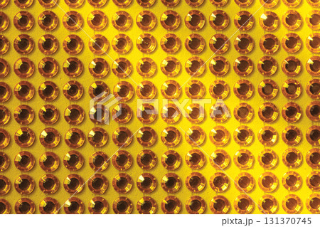 Rows of artificial rhinestones on a yellow background 131370745