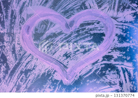 Heart shape on a frozen window. Abstract photo background in pink light. Valentine's day and love concept 131370774