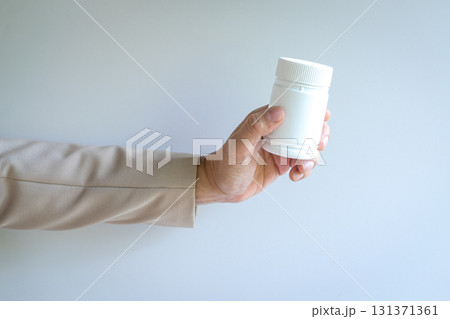 Person holding a white color bottle. 131371361
