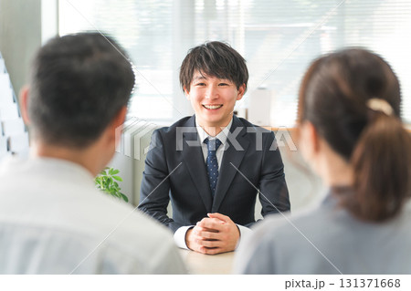 ショールーム・商談スペースで接客する若いアジア人ビジネスマンと客の夫婦 131371668