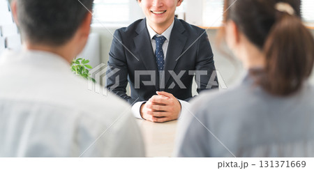 ショールーム・商談スペースで接客する若いアジア人ビジネスマンと客の夫婦 131371669
