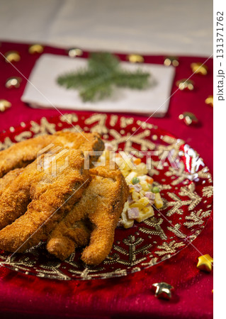 Fried carp with potato salad Christmas dinner on red tablecloth Fried carp with potato salad Christmas dinner on red tablecloth 131371762