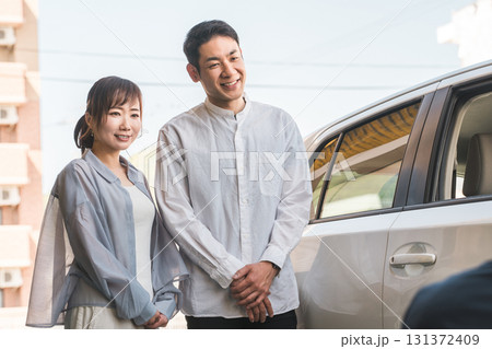自動車購入・査定・買取にきた夫婦を接客するセールスマンの若いアジア人男性 131372409