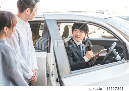 自動車購入・査定・買取にきた夫婦を接客するセールスマンの若いアジア人男性 131372414