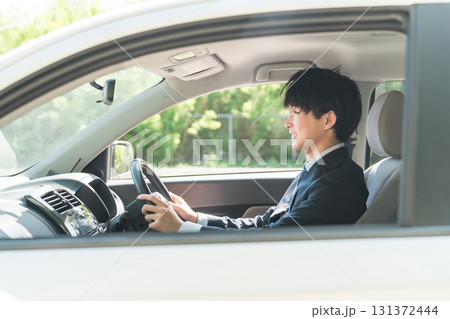 車を運転するスーツ姿の若い男性ビジネスマン 車を運転するスーツ姿の若い男性ビジネスマン 131372444