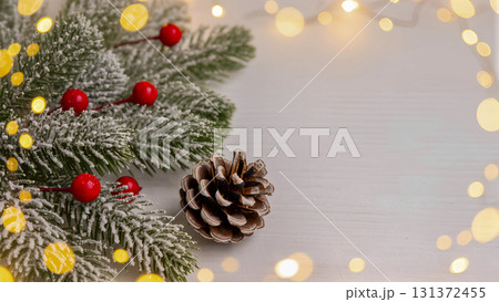 Winter holiday background: Snow-covered fir branches, pine cone and golden bokeh lights. Winter holiday background: Snow-covered fir branches, pine cone and golden bokeh lights. 131372455