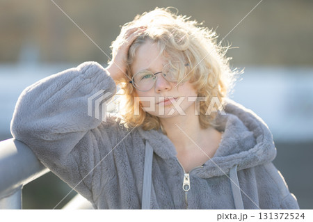 Young person posing with blonde hair and glasses Young person posing with blonde hair and glasses 131372524