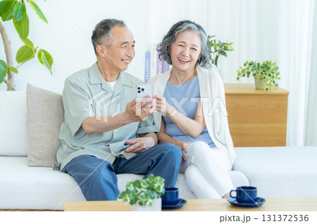 リビングでスマホを見るシニア夫婦 リビングでスマホを見るシニア夫婦 131372536