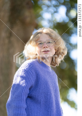 Young blonde person wearing glasses and purple sweater Young blonde person wearing glasses and purple sweater 131372571