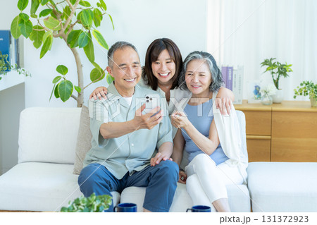 リビングでスマホを見るシニア夫婦と子供 リビングでスマホを見るシニア夫婦と子供 131372923