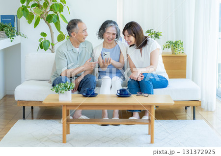 リビングでスマホを見るシニア夫婦と子供 131372925