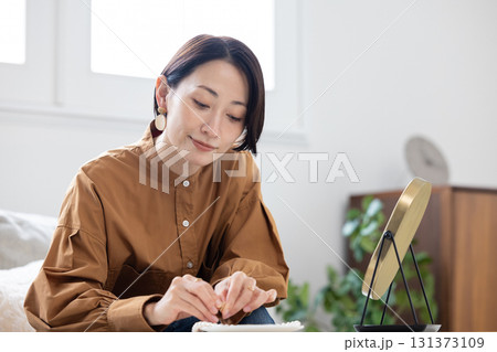 リビングで鏡を見ながらイヤリングをつける女性 リビングで鏡を見ながらイヤリングをつける女性 131373109